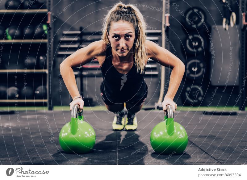 Muscular woman on hands in dumbbells in modern gym on blurred background exercise flexible strong muscular sport club female stand shorts healthy training