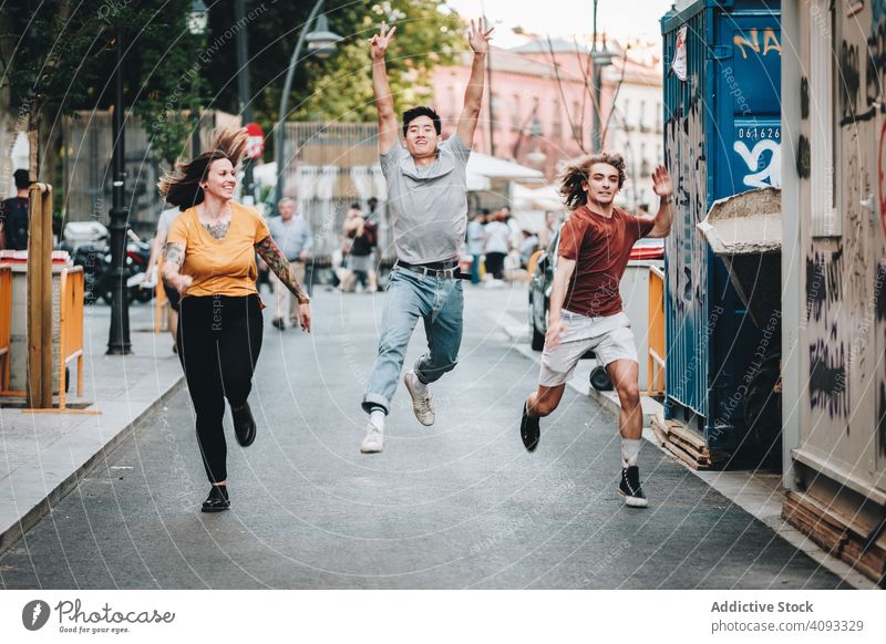 Funny multiracial friends having fun and running along city street pretend together diverse funny smile competitive hurry urban casual modern late fast enjoying