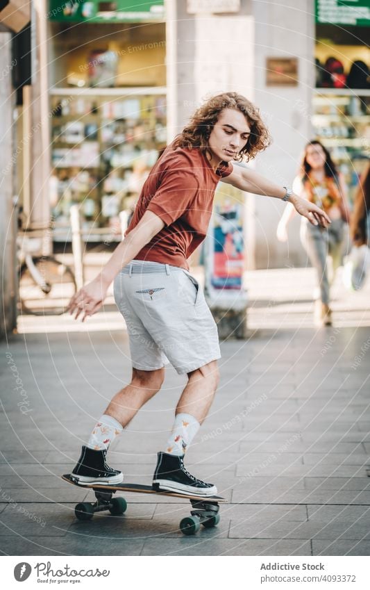 Confident man riding longboard across city street ride urban freestyle trick focused casual cool confident sunny summer pavement balance young adult skater