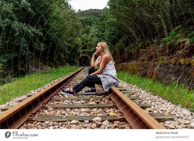 Woman sitting on railway though greenery part of road woman extreme forest travel journey grove railroad voyage transport passenger trip smart tourism steel