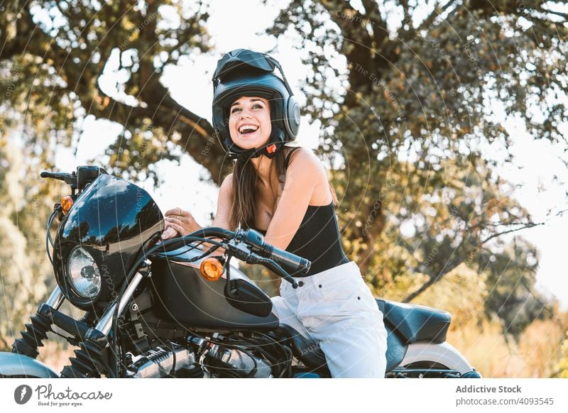 Attentive woman in helmet sitting on parked motorcycle at rural area cool confident freedom serious shiny clean beautiful attractive charming modern motorbike