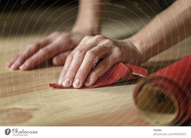 Graceful female hands are holding sandpaper. Rubbing wooden floor, house work, apartment renovation. Close-up. graceful caucasian rubbung close-up home tool