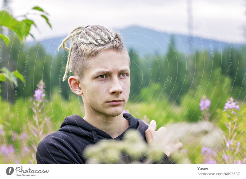 Young handsome man is standing in the middle of wild field of flowers. Summer activity, holidays in mountains, hiking, healthy lifestyle. young caucasian