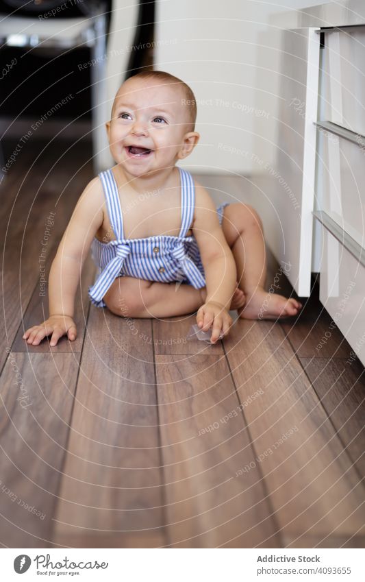 Happy baby sitting on floor in kitchen happy home cozy counter parquet fun child toddler childhood kid barefoot excited innocence rest relax wooden lumber