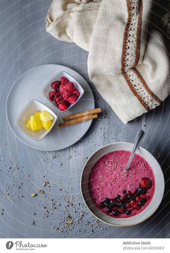 Smoothie bowl with fresh berries and sesame served on table smoothie mango cut cinnamon kitchen cloth rustic super food plate spoon wooden colorful raspberry