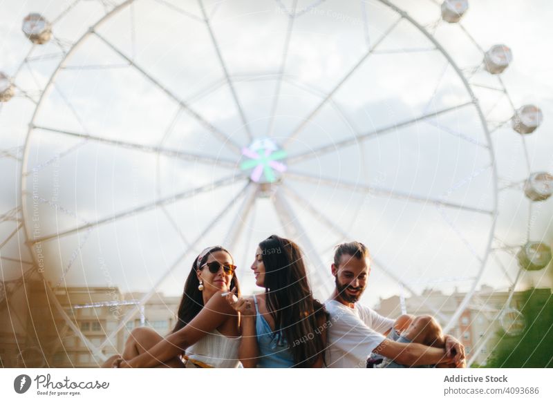 Peaceful friends relaxing and sitting next to Ferris wheel at fairground dream ferris wheel rest inspiration peaceful carefree tanned smile parapet amusement