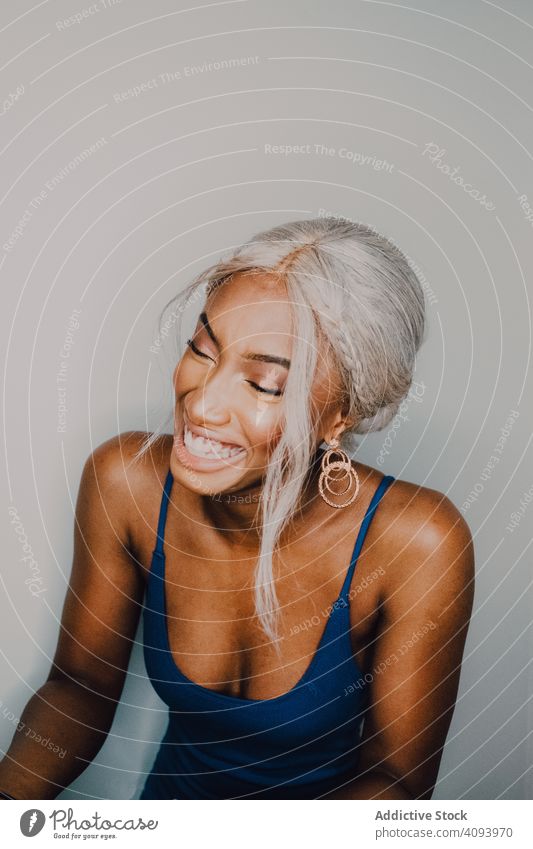 Charming Black woman in blue trendy dress laughing fashionable style vogue glamour individuality beauty model gloss female adult accessory earrings wearing