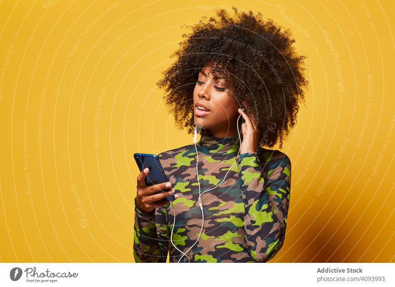 Trendy young woman with smartphone listening to music trendy color headphones fashion afro african american black ethnic style fun sound casual entertainment