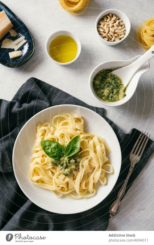 Served plate of pesto pasta next to bowl of sauce on table kitchen fresh cooked white garlic oil basil tagliatelle cloth food italian healthy ingredient dinner