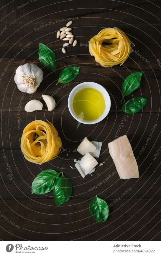 Ingredients for pesto pasta arranged at table ingredient arrangement fresh herb cheese garlic oil tagliatelle rustic wooden food basil parmesan seeds cuisine