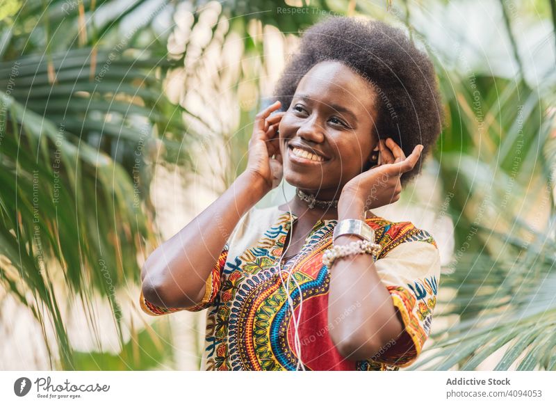 Smiling black woman listening to music earphones smile african palm traditional colorful joy female ethnic cheerful happy tune melody audio song glad lady