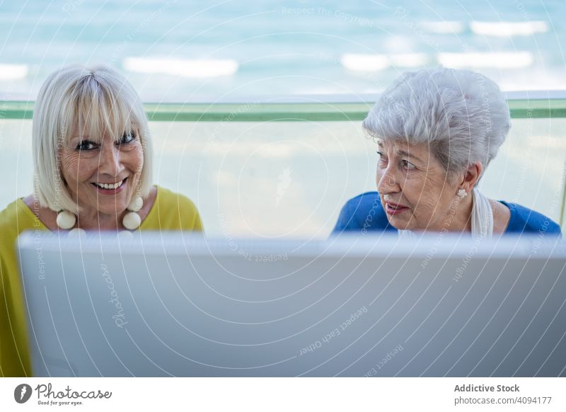 Elderly women using computer tablet elderly friend balcony resort social media senior mature together friendship device gadget monitor terrace elegant stylish