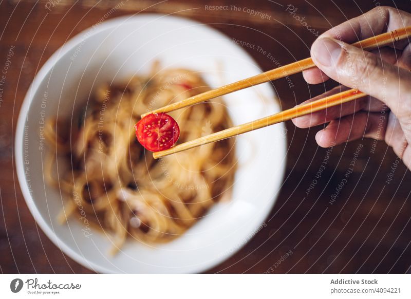 Faceless person eating dinner with chopsticks cherry tomato noodles food meal cuisine dish prawn asian food seafood oriental gourmet cooked healthy bowl spicy