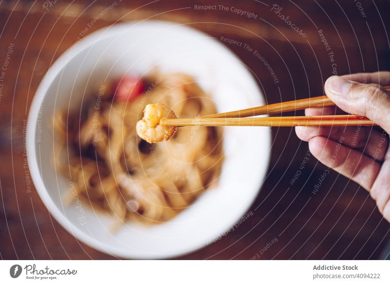Faceless person eating dinner with chopsticks shrimp noodles food meal cuisine dish prawn asian food seafood oriental gourmet cooked healthy bowl spicy lunch