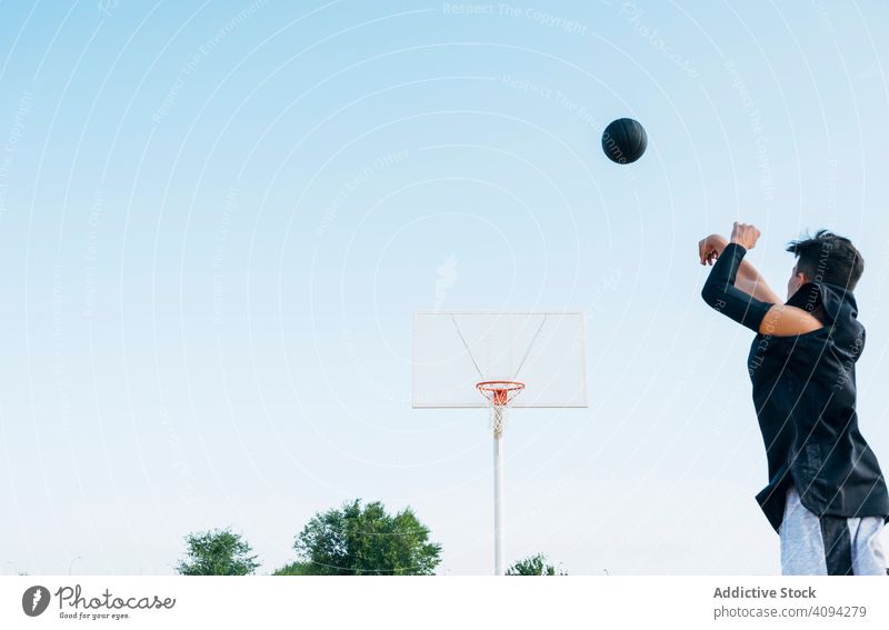 Young man playing on yellow basketball court outdoor. athlete competition sports equipment adult recreation action portrait active activity asphalt athletic