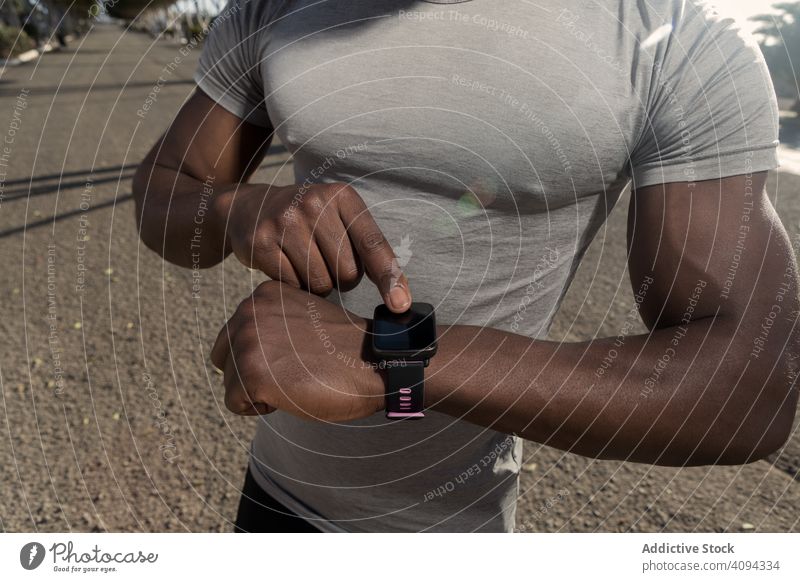 Ethnic sportsman using tracker on street use smart watch run athletic ethnic road start preparation device gadget wearable male muscle slender interaction