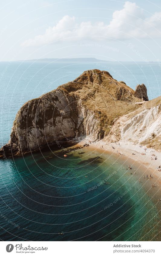 Sandy beach in bay by cliff sea rock landscape durdle door water seascape picturesque travel destination resort tourism limestone formation scenery people relax
