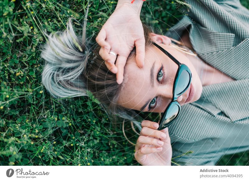 Woman in stylish suit and sunglasses lying in grass businesswoman rest green break relaxation trendy manager career entrepreneur gadget modern creative lady