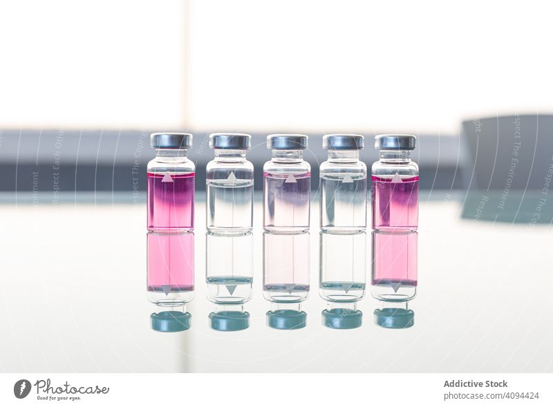 Scientific or medical samples on glass table liquid vial laboratory chemical flask scientific ampoule research solution fluid medicament substance pink gradient