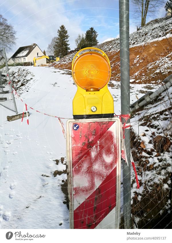 Warning beacon with red graffiti and yellow flashing light in winter with snow on a construction site in Oerlinghausen near Bielefeld on the Hermannsweg in the Teutoburg Forest in East Westphalia-Lippe