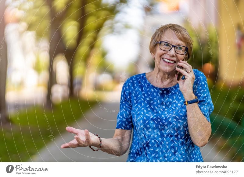 Portrait of a senior woman using mobile phone outdoors people mature casual female Caucasian elderly old grandmother pensioner grandparent retired retirement