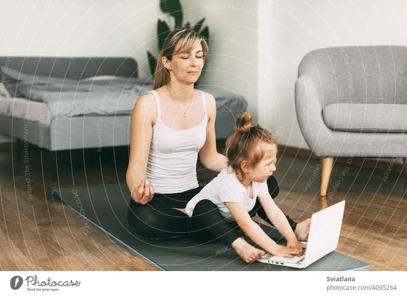 A beautiful young woman and her adorable little daughter smile and meditate after a workout together yoga mom meditation home smiling doing childhood fitness