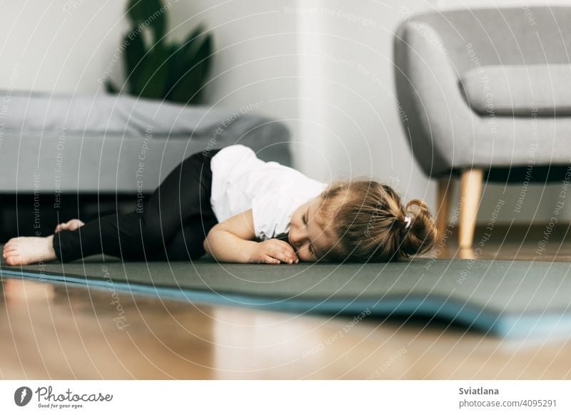 A little girl lies on a yoga mat in the bedroom and rests after a game baby happy lying floor play small child cute resting person human indoors adorable people