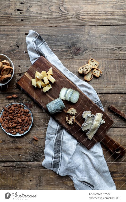 Croutons and nuts near board with cheese table crouton cut almond raisin cuisine food wooden knife bread assorted various slice mold appetizing gourmet snack