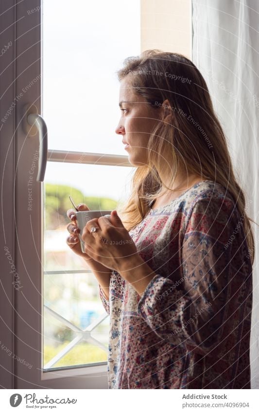 Girl in a shirt with a cup of coffee or tea looking out the window in the morning woman pretty awake joy girl beauty indoors view home rest lifestyle beautiful