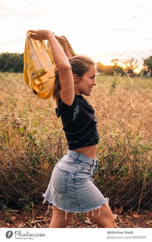 Happy female on meadow in summer woman field happy content casual shirt romantic take off bronzed fence metal chain link nature countryside beauty leisure