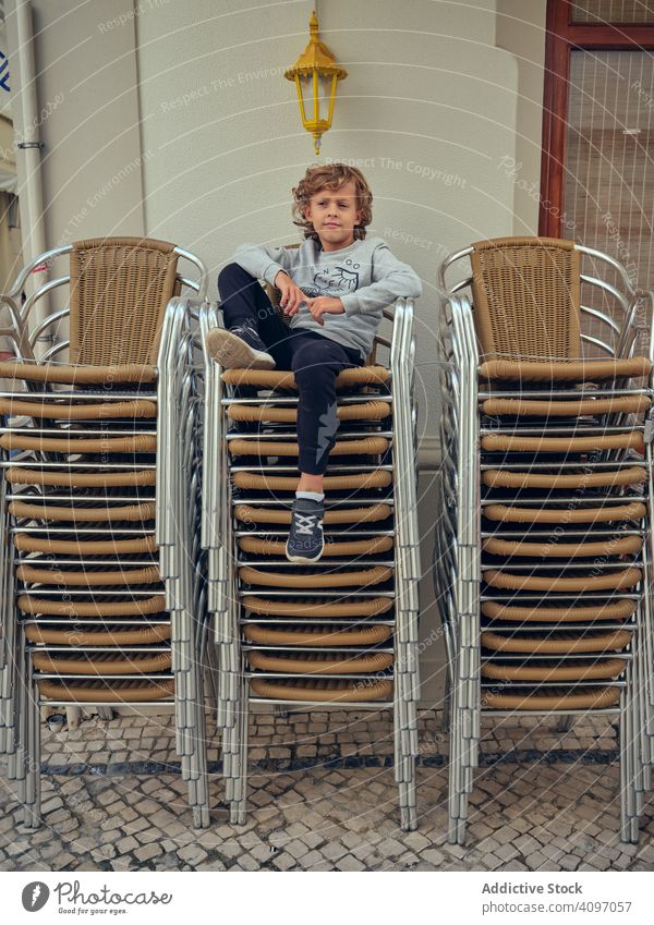 Wistful boy relaxing on armchair on terrace street rest pensive wistful child comfortable portugal sit house happy fun smart leisure cheerful calm cute couch