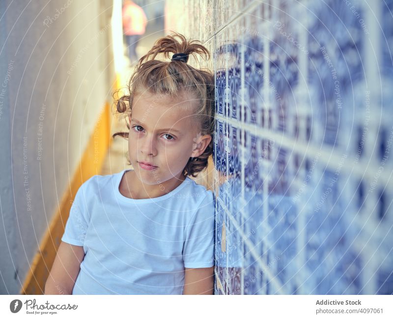 Serious kid leaning on street wall child serious portugal thoughtful standing alley narrow stylish pretty childhood adventure town shirt hairstyle modern