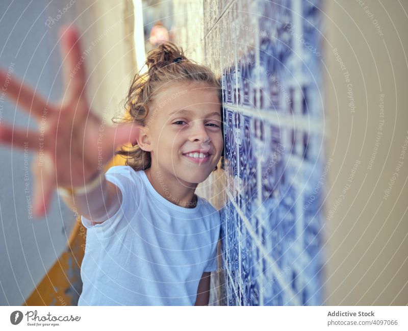 Smiling kid standing on street child smile portugal content lean wall happy childhood sunlight free time cheerful young relax rest vacation holiday summer
