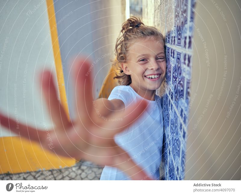 Smiling kid standing on street child smile portugal content lean wall happy childhood sunlight free time cheerful young relax rest vacation holiday summer