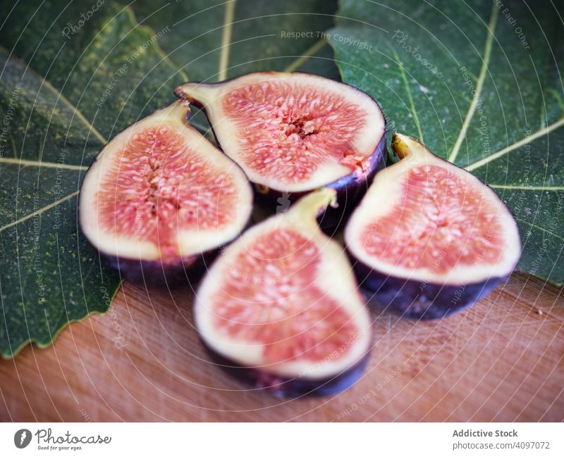 Several pieces of fig over table and green leaves leaf mature rustic fresh fruits rural tree food wooden traditional closeup spain home edible figs ripe bright