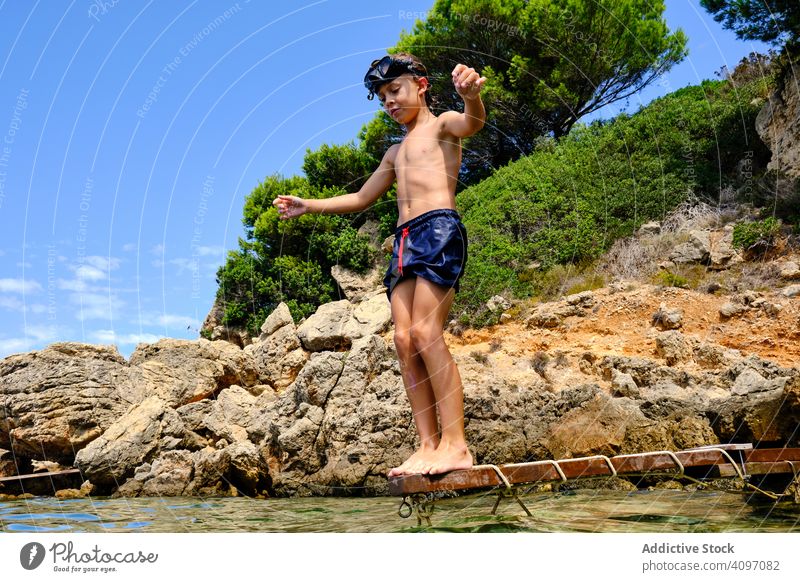 Little boy getting ready to jump in water sea dive summer seashore balance child mask coast travel active rocky tourism cliff sporty recreation wet energy
