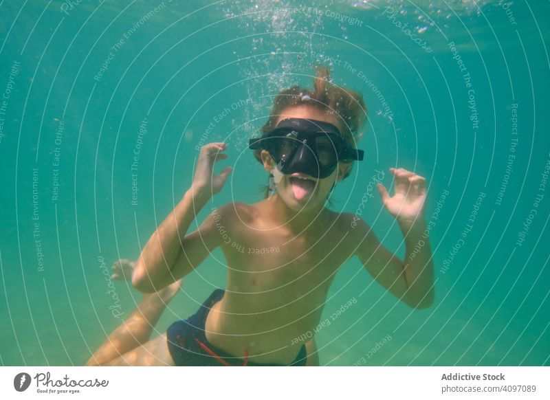 Playful boy in mask swimming underwater dive fun tongue out active sea grimace kid making face transparent float clear athlete playful cheerful ocean energy