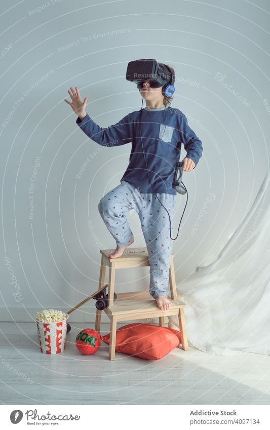Happy child in VR headset vr play goggles win joystick goal sport popcorn leisure fun arms raised pretend game happy weekend simulator interaction enjoy device