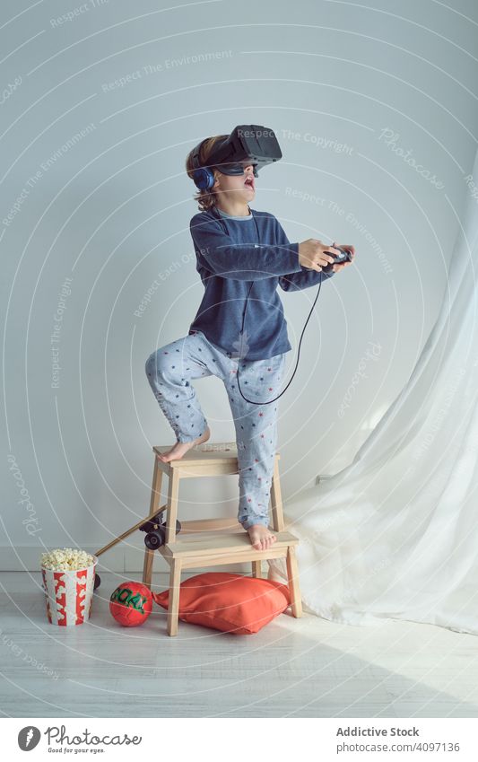 Happy child in VR headset vr play goggles win joystick goal sport popcorn leisure fun arms raised pretend game happy weekend simulator interaction enjoy device