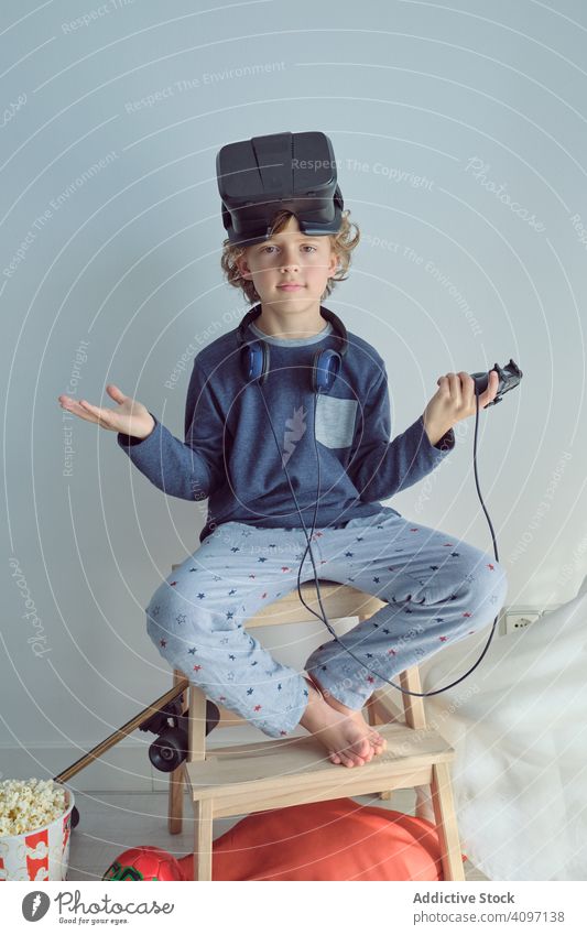 Boy with VR glasses on head looking at camera boy vr goggles popcorn entertainment chill dream home comfort weekend cinema holiday headset fun leisure activity