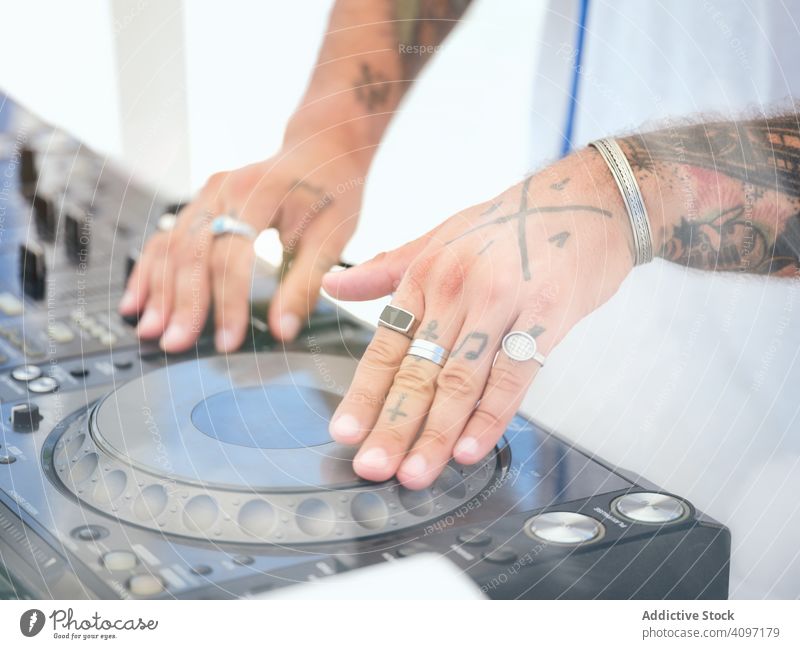 Anonymous DJ tuning music during party dj tune audio board mixer work tattoo club stage rings entertainment sound button turn hand body part hands control
