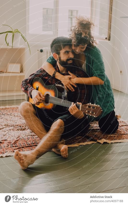 Cheerful couple playing guitar cheerful laugh home fun casual domestic hobby music tender musician happy guitarist adult lifestyle together smile relaxing
