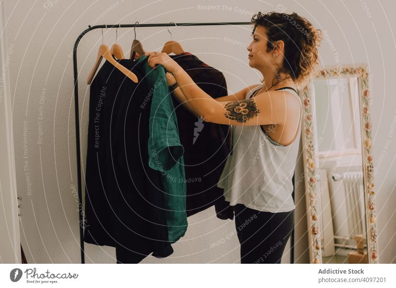 Happy woman hanging clothing on clothes rail at home happy content casual shirt hanger barefoot smile minimalistic stand young adult unpacking lifestyle wear