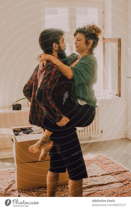 Happy couple embracing in room next to cardboard boxes moving happy embrace affectionate cuddling smile home holding on hands stand casual modern house