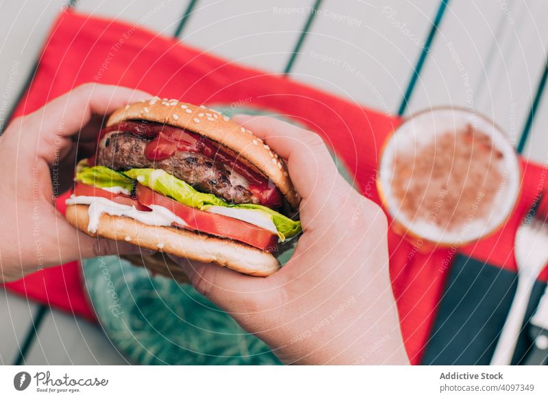 Hands holding a cheeseburger with lettuce and tomato bun classic unhealthy table food meal onion beef delicious bbq grill snack hamburger american gourmet beer