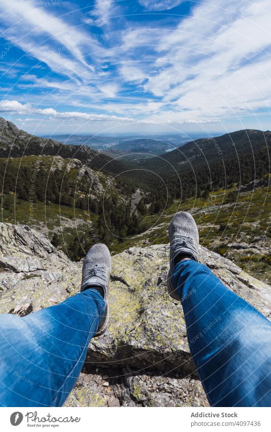 Person sitting dangling legs on stone above mountain valley cloud sky nature travel park forest landscape scenic hill rocky rural green scenery blue beautiful