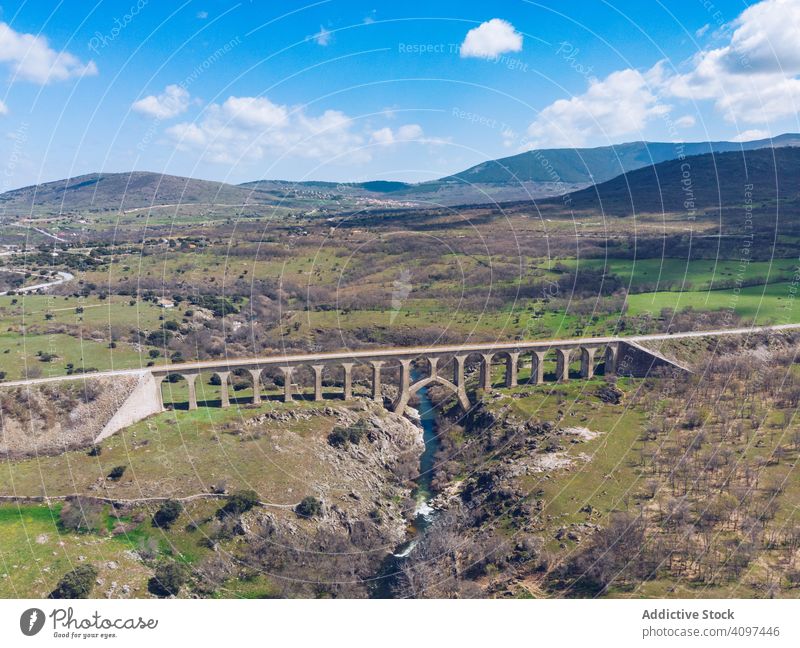 Concrete bridge over mountain river at picturesque green valley viaduct cloudy concrete scenic majestic overpass hilly colorful horizon travel road landscape