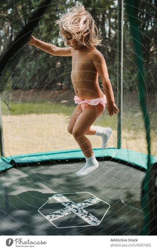 Little girl jumping on trampoline garden fun joy happy recreation activity lifestyle playground summer exercise childhood little action energy power kid gymnast