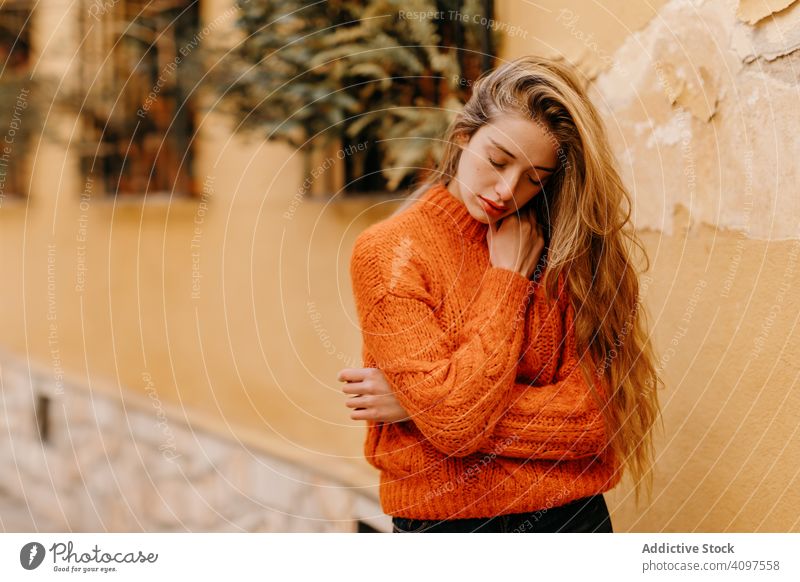 Young lady in sweater near house with potted plants woman stylish sensual window street touching chin young female model fashion trendy vogue glamour cool