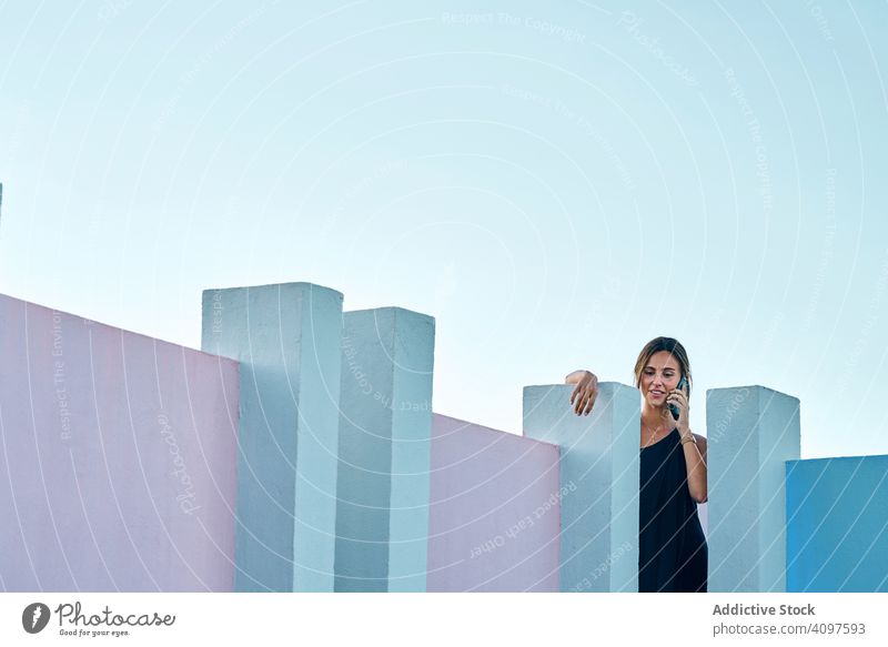 Woman standing on the top of a blue building using mobile phone woman casual elegant construction structure geometric architecture urban facade wall abstract